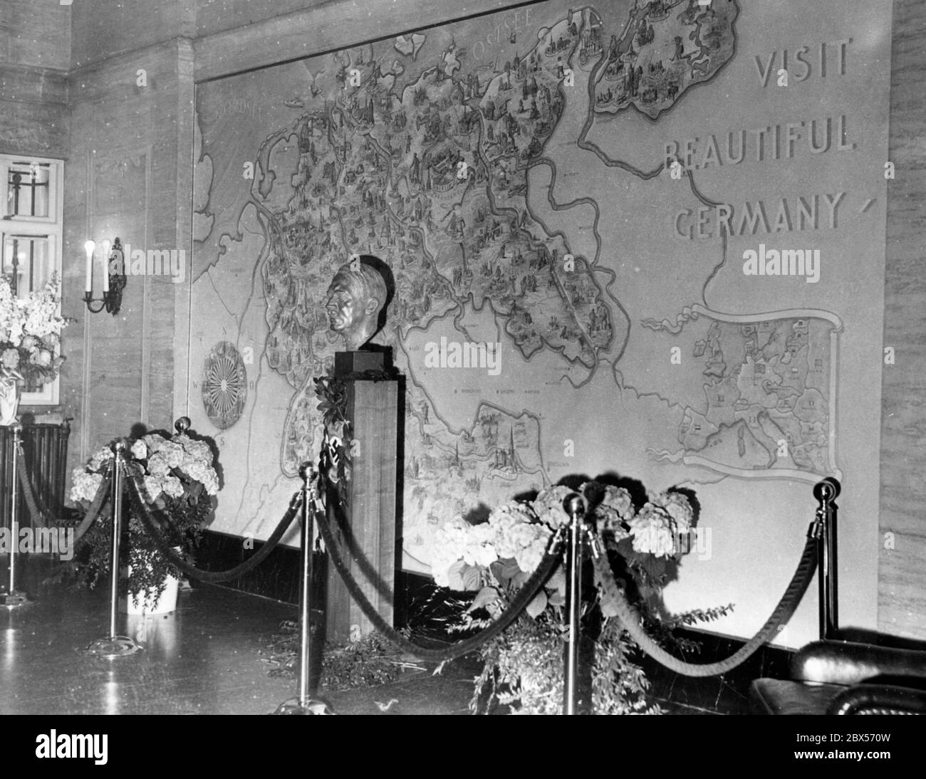 Une agence de voyages du Reich allemand est ouverte à New York par une cérémonie de fête. Ici, dans la salle du Deutsche Reichsbahn se trouve une grande carte murale du Reich (entre une boussole rose à gauche et une petite carte de l'Europe à droite) et un buste d'Adolf Hitler. Sur la carte, il y a l'invitation 'visiter la belle Allemagne'. Banque D'Images