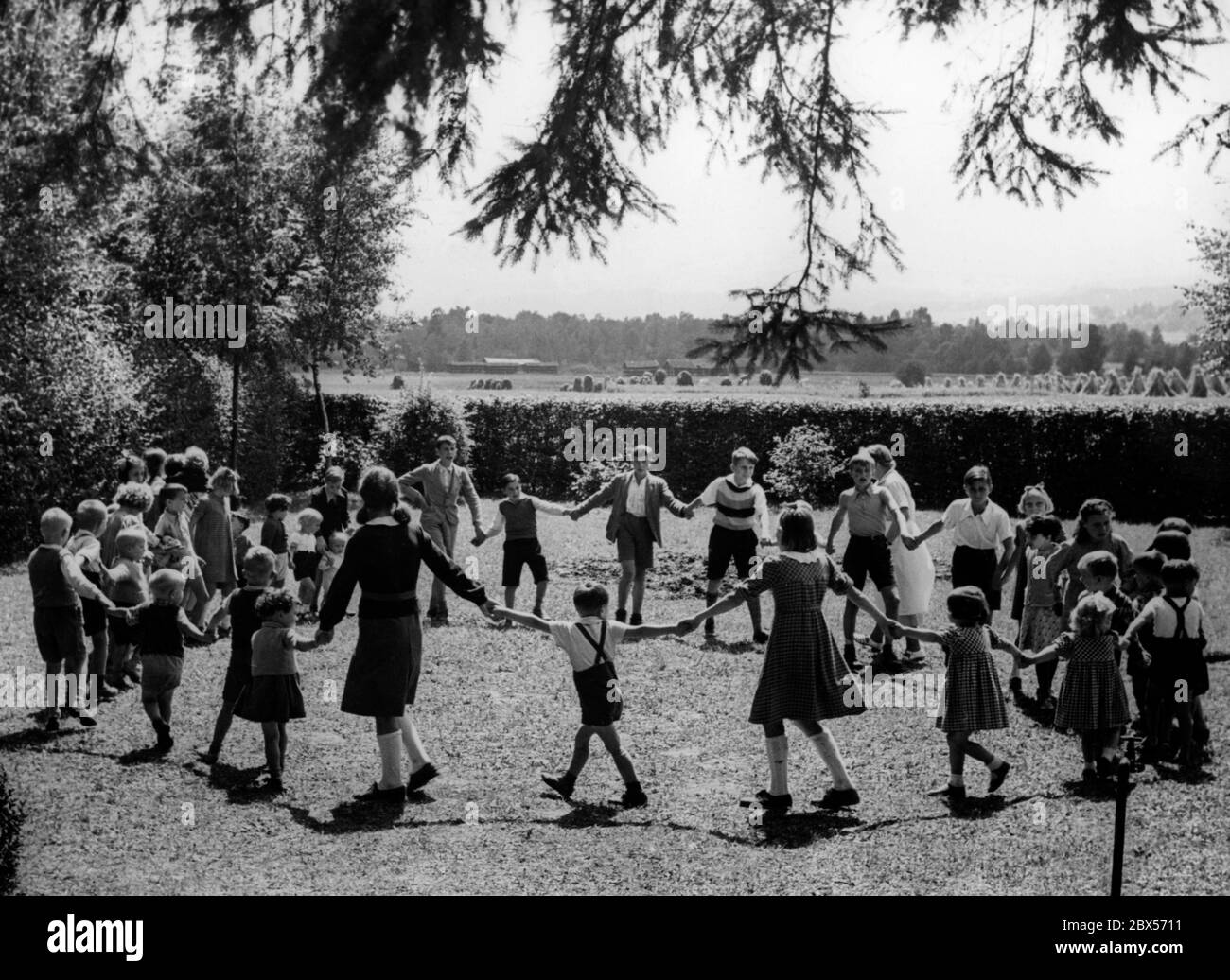 Les enfants passent leur temps libre dans le jardin devant la maison pour les rapatriés appartenant à l'organisation étrangère NSDAP à Prien on Chiemsee. Banque D'Images