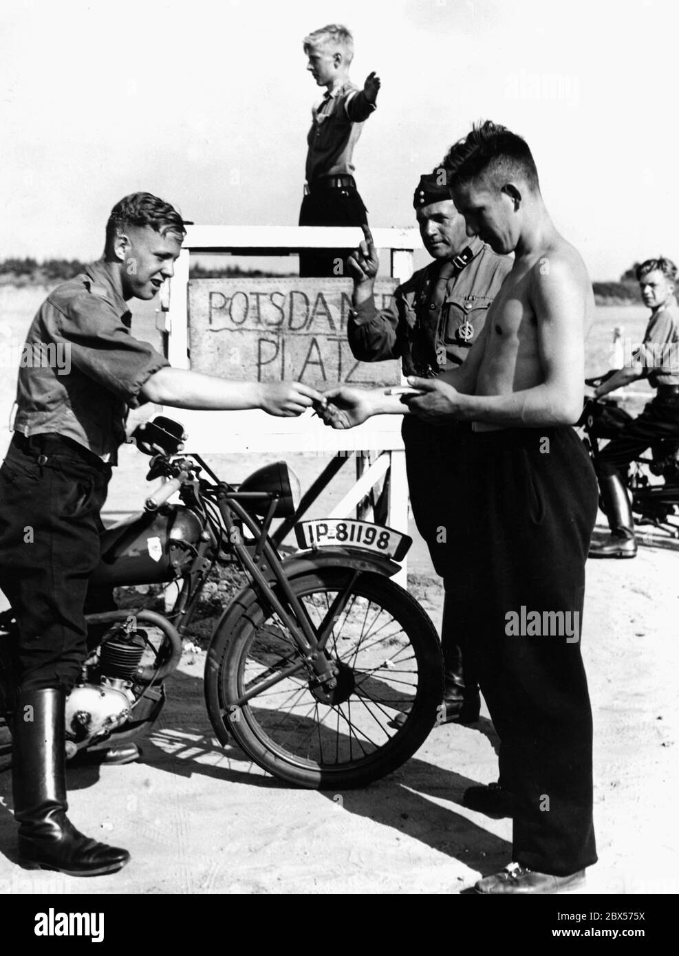 Lors des leçons de conduite à la « Potsdamer Platz » dans le Nordoer Heide, un contrevenant de la circulation automobile HJ est rébuté par un membre de NSKK. Le conducteur de la moto doit payer une amende de cent. Probablement une photo mise en scène. La moto est de type DKW RT 98 cc. En arrière-plan, un poste de signalisation indique les signaux. Banque D'Images