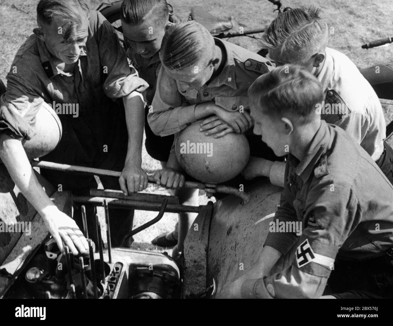 Leçon d'objet sur un moteur de voiture démantelé dans le camp 'Potsdamer Platz' dans le Nordoer Heide. Les membres de la Jeunesse d'Hitler se tiennent autour de la voiture et écoutent le professeur qui explique et présente. Banque D'Images