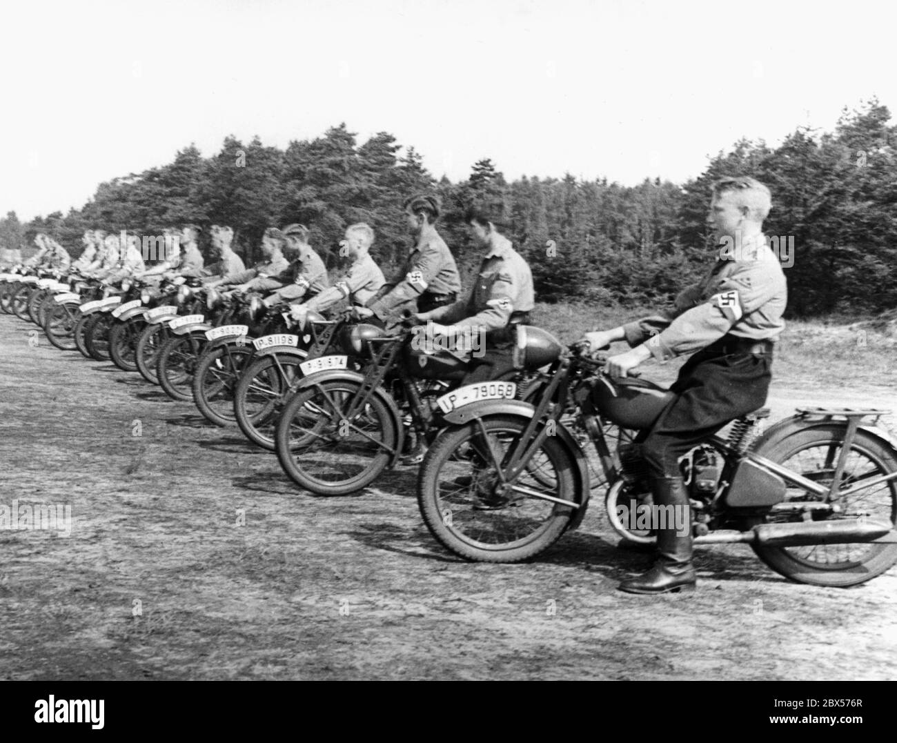 Les membres de la Jeunesse de Motor Hitler se tiennent dans une rangée avec leurs motos dans le camp de 'Potsdamer Platz' dans le Nordoer Heide. Ils sont sur le point de partir pour un entraînement. Ils sont assis sur des motos de type DKW KS 200. Banque D'Images