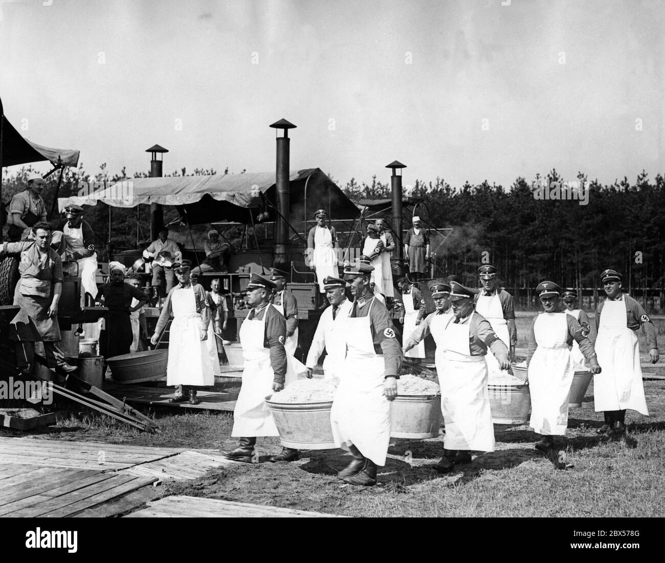Dans le camp Harnischschlag du NSDAP de Berlin, la cuisine de 10000 hommes est faite dans des tentes de cuisine. Les aides de cuisine portent la choucroute dans de grands bols au centième poids. Banque D'Images