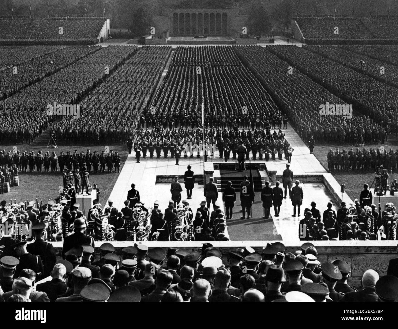 Adolf Hitler parle de la chaire de la Luitpold Arena aux organisations nazies qui se sont mises en file pour le rassemblement du parti nazi de Nuremberg. En arrière-plan est l'Ehrenhalle. Deux équipes de film se trouvent à gauche et à droite. Banque D'Images