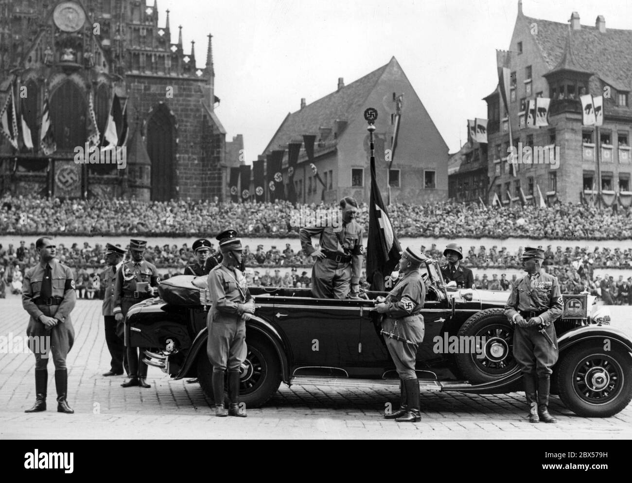 Adolf Hitler parle à Hermann Goering en se tenant dans sa Mercedes pendant la marche des organisations nazies sur la soi-disant Adolf-Hitler-Platz. Sur la droite Franz Pfeffer von Salomon, sur la gauche Rudolf Hess et Viktor Lutze. En arrière-plan, les tribunes et le front de l'église notre-Dame Unsere Lieber Frau. Banque D'Images