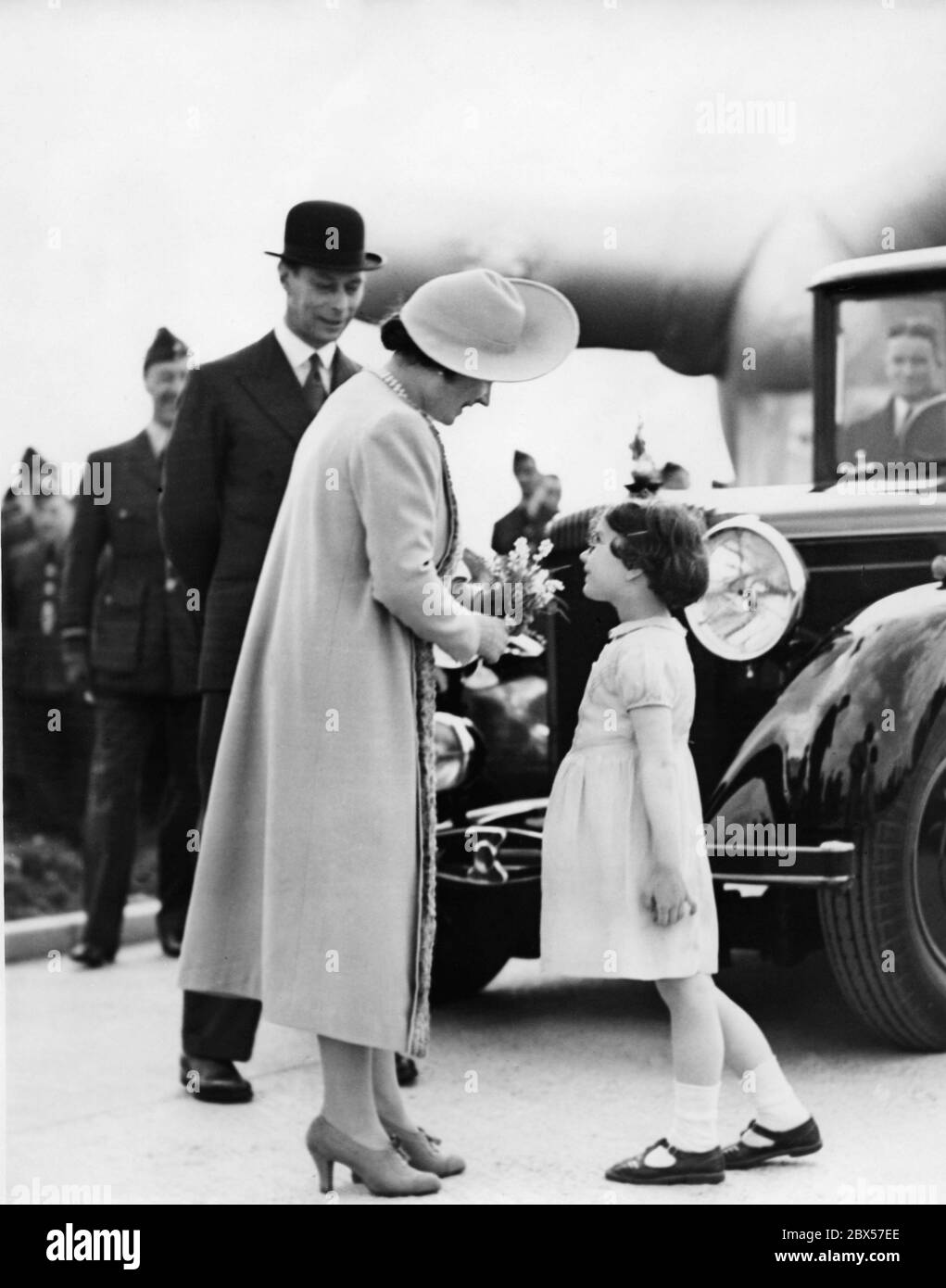 La reine Elizabeth reçoit un bouquet de la santé d'hiver d'Ann Emery pour bonne chance, à son arrivée à l'exposition Balloon Barage à Hook, près de Kingston (Surrey). En arrière-plan, le roi George VI Banque D'Images