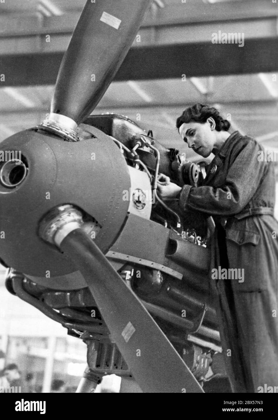 "La patrie se tient d'épaule à épaule avec le devant" lit au dos de cette photo de 1943, qui montre un travailleur ajustant le moteur d'un Messerschmitt BF 109. Banque D'Images