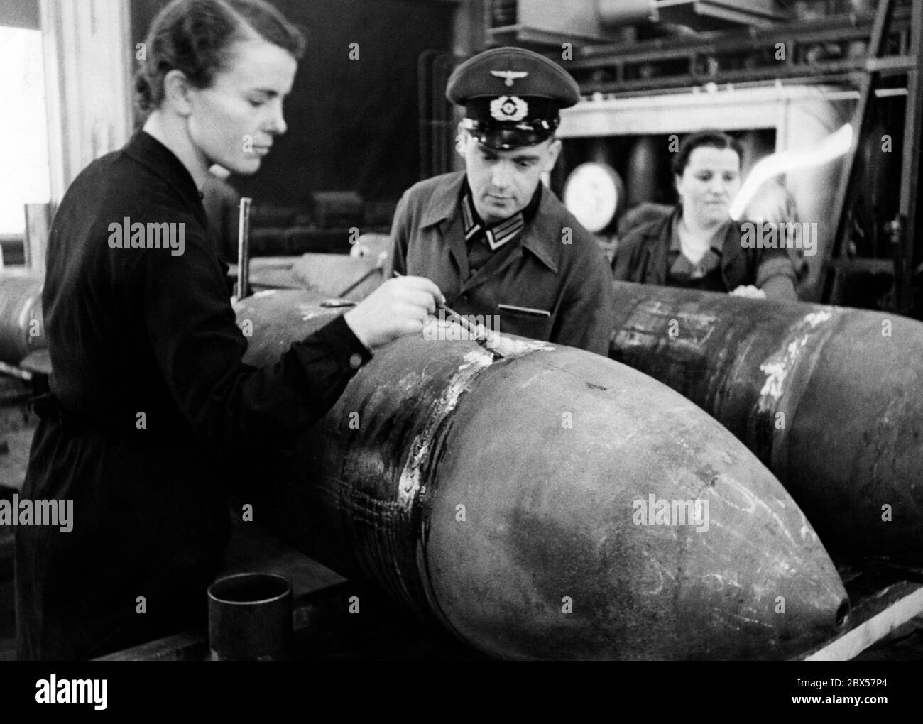 Un travailleur de l'industrie de l'armement vérifie la densité des cordons de soudure d'une bombe en leur faisant couler de l'eau savonneuse tout en appliquant simultanément une pression d'air. La date est manquante, mais la note manuscrite 'bombes pour l'Angleterre' au dos de la photo, qui a également été souvent notée sur d'autres photos de ce type, indique qu'elle a été prise en 1941 ou 1942. Banque D'Images