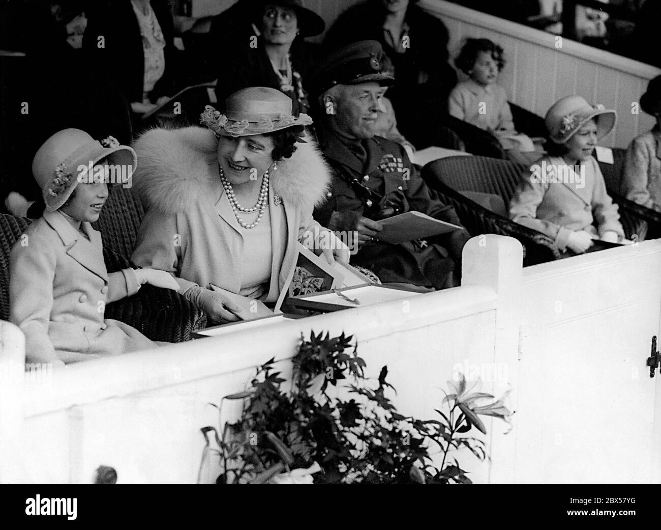 Elizabeth II, sa mère, la reine Elizabeth, et sa sœur, la princesse Margaret Rose, assistent à une répétition du Tattoo militaire d'Aldershot, un événement militaire majeur à l'arène Rushmoor. Plusieurs milliers d'enfants ont été autorisés à regarder l'événement gratuitement. De gauche à droite : la reine Elizabeth II, la reine Elizabeth, le général Sir Frederick Gaythorne-Hardy, le commandant en chef d'Aldershot et la princesse Margaret Rose. Banque D'Images