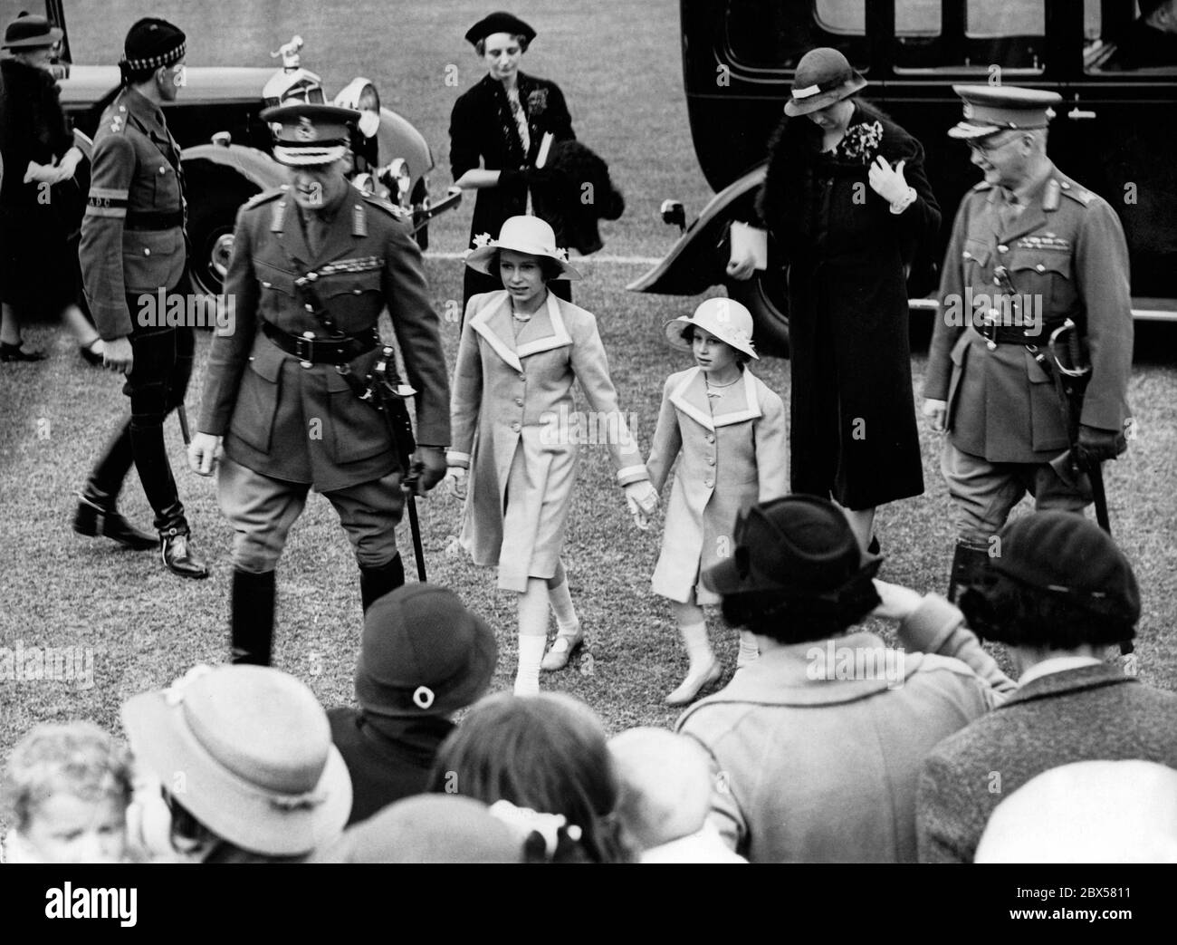 Elizabeth II sur son chemin vers la répétition du Tattoo militaire d'Aldershot avec sa petite sœur, la princesse Margaret Rose et la reine Elizabeth (derrière eux). Banque D'Images