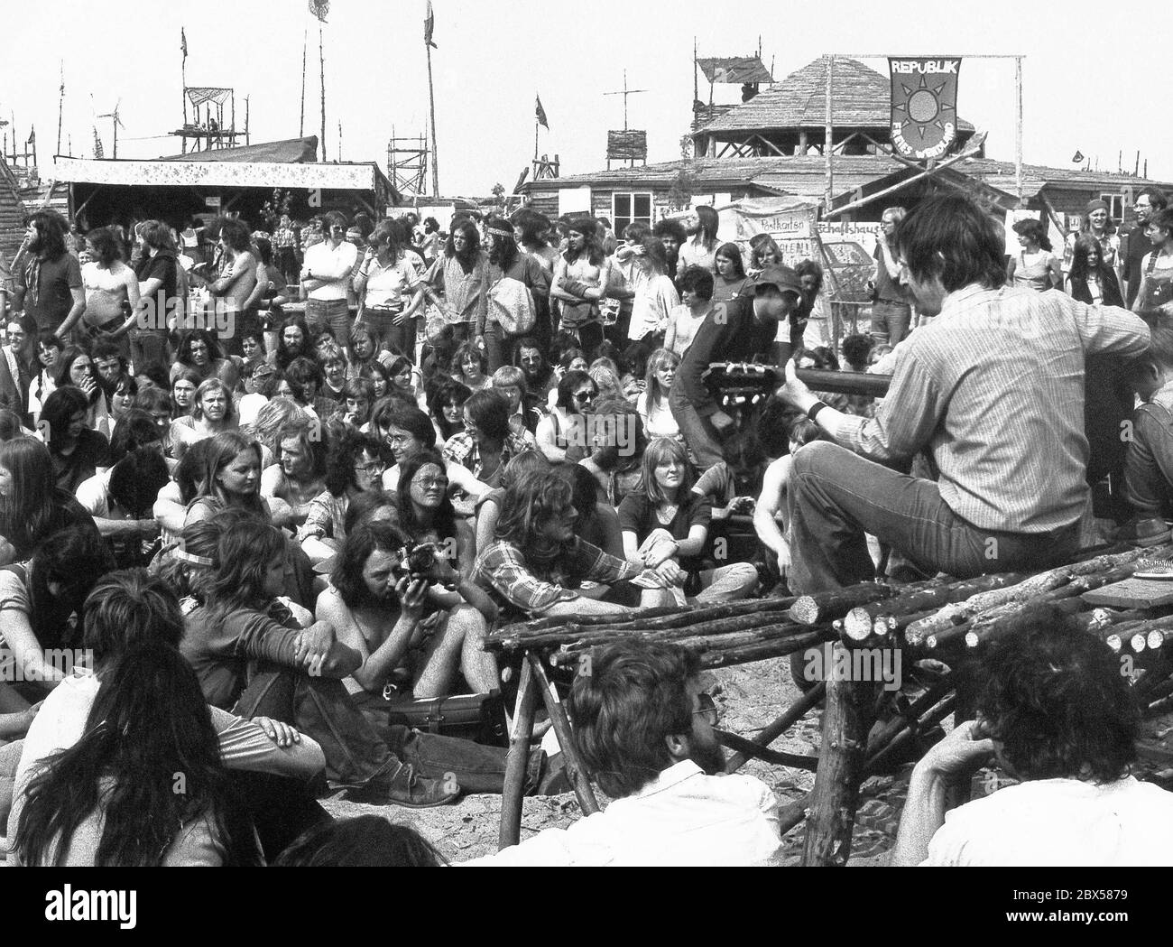 L'auteur-compositeur Wolf Biermann apparaît dans le village de refuge de la 'République libre de Wendland'. En quelques jours, un village de plus de 100 huttes a été construit sur une forêt désolée, déjà brûlée. La Tiefbohrstelle 1004 (site de forage 1004), l'un des nombreux avec lesquels le dôme de sel de Gorleben doit être examiné pour sa pertinence en tant que dépôt de déchets radioactifs, est occupé par des adversaires de l'énergie nucléaire de toute l'Allemagne. Banque D'Images