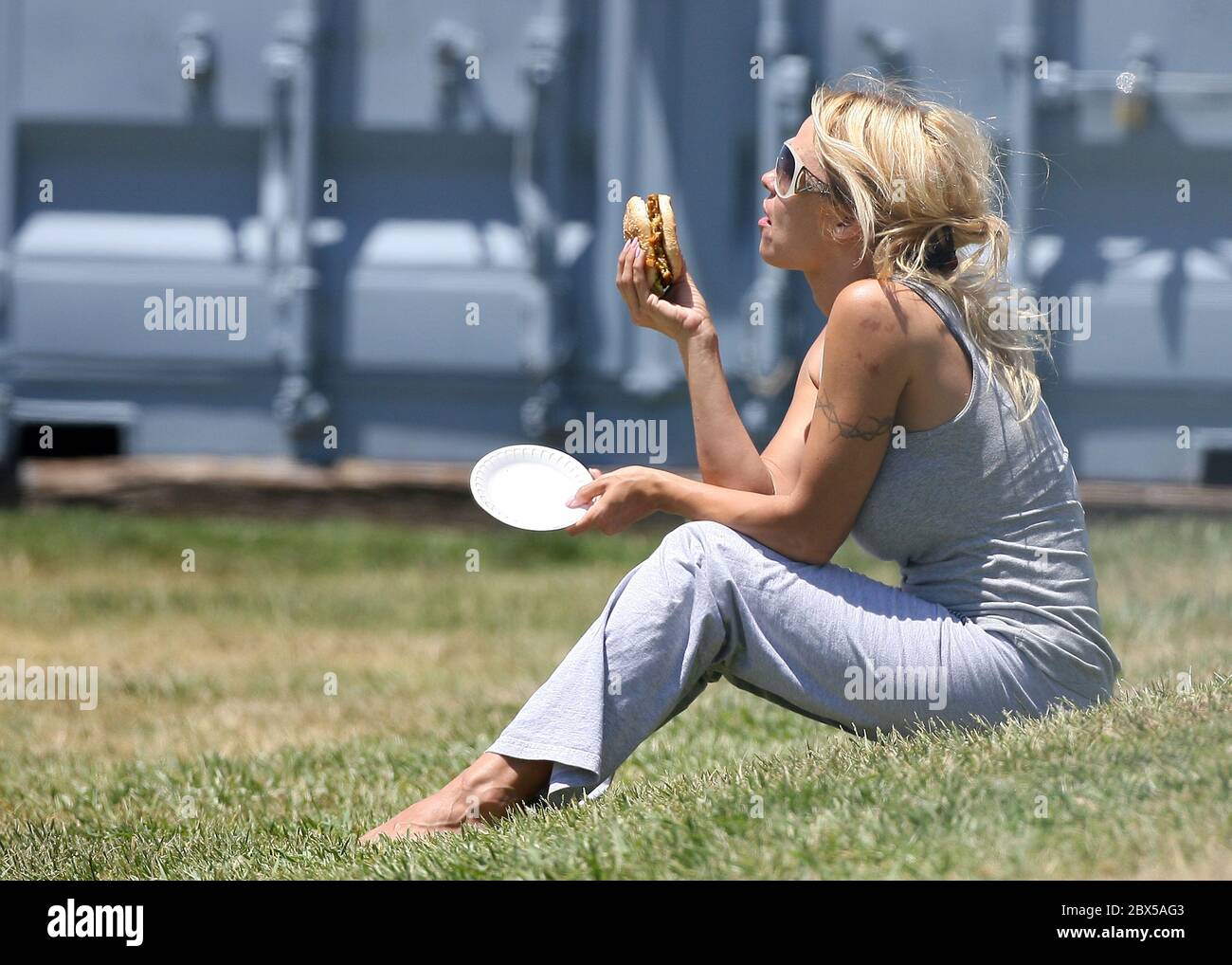 Pamela Anderson assis sur l'herbe, manger du hamburger à Malibu, CA mai 2008 Banque D'Images