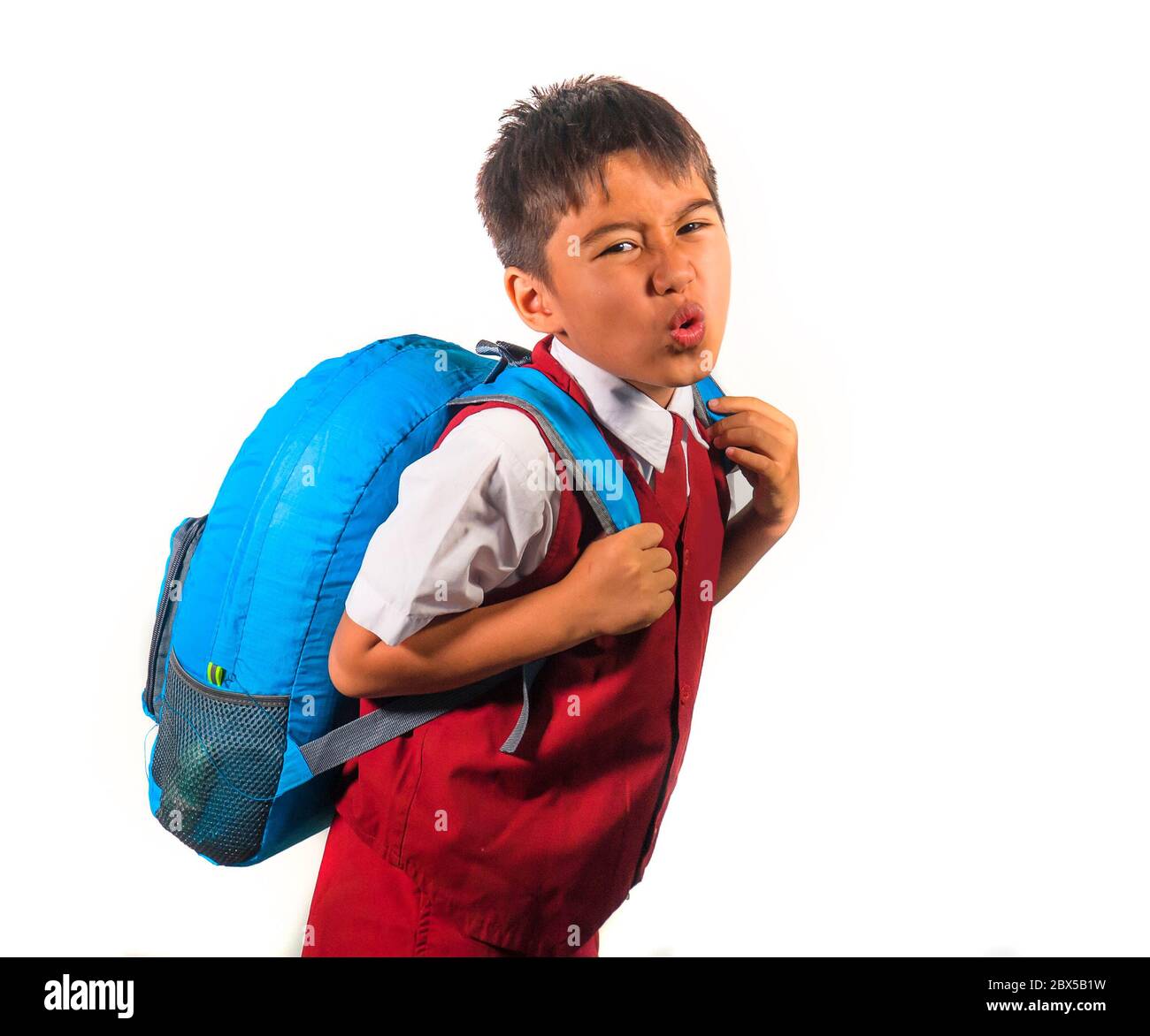 enfant doux de 7 ou 8 ans dans un sac de transport uniforme plein de livres se sentant contrarié et se plaignant du poids du sac à dos dans l'école paresseuse unha Banque D'Images