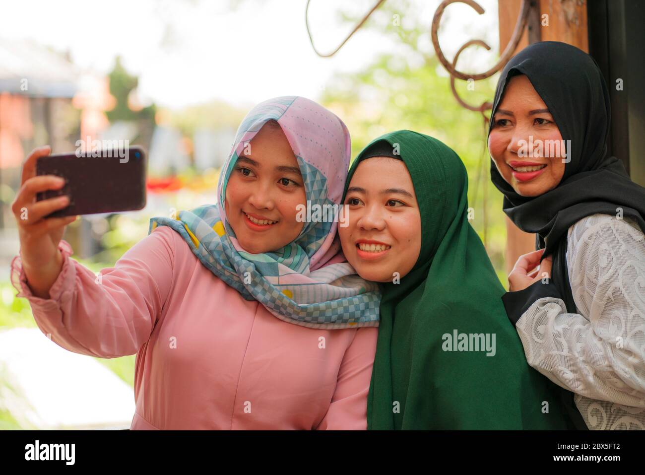 Femme musulmane et ses filles adolescentes . Joyeuses sœurs indonésiennes  asiatiques qui prennent le selfie avec sa mère en portant le foulard  islamique traditionnel hijab Photo Stock - Alamy
