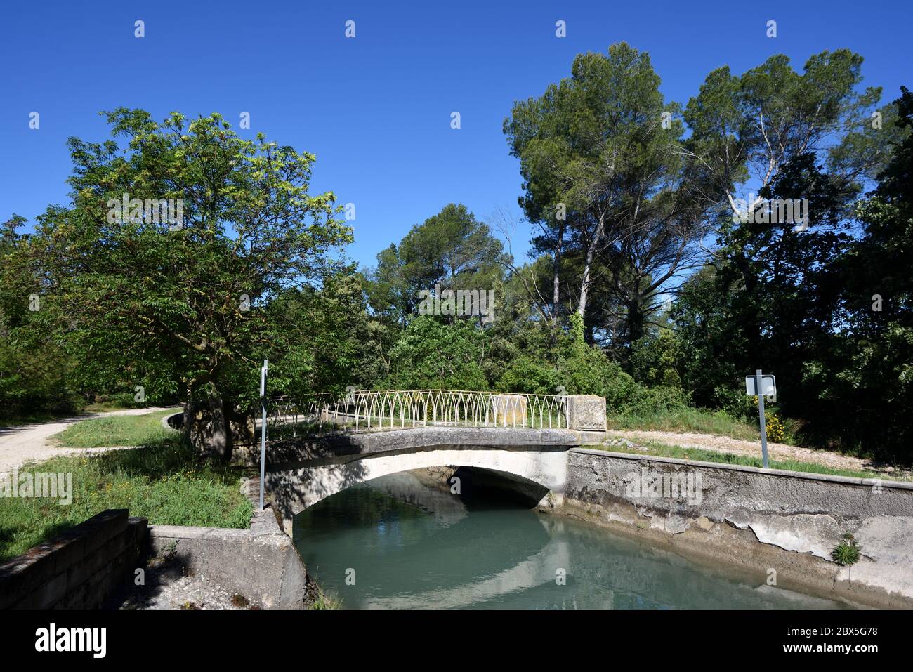 Petit pont en béton et chemin de promenade ou sentier de promenade le long des rives du canal de Marseille près de Ventabren Provence France Banque D'Images