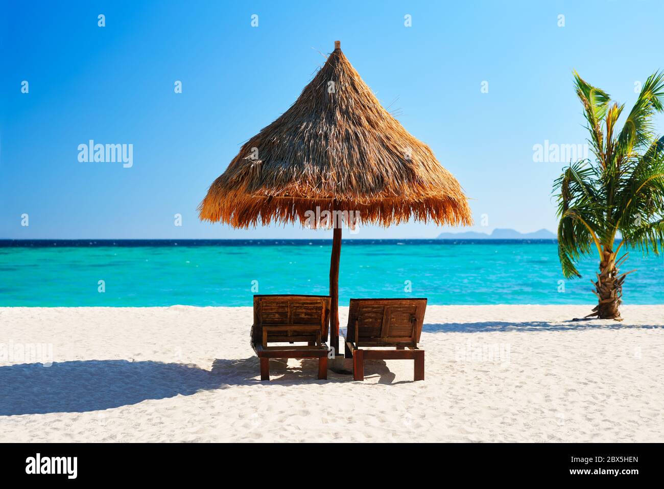 Belle plage tropicale avec deux chaises longues et parasol. Concept de voyage et de vacances d'été Banque D'Images