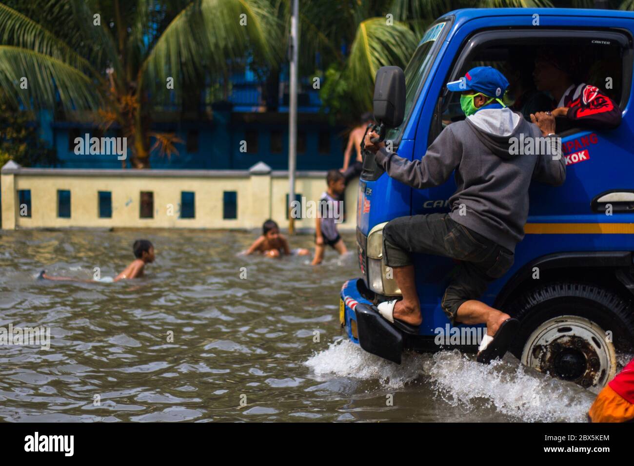 Jakarta, DKI Jakarta, Indonésie. 5 juin 2020. Un homme porte un masque incliné sur un camion pour éviter une flaque d'eau de mer qui absorbe la zone côtière de Jakarta. En raison de l'eau de mer répandue le long du littoral nord a provoqué l'inondation de certaines zones en Indonésie. Crédit : Muhammad Zaenuddin/ZUMA Wire/Alay Live News Banque D'Images