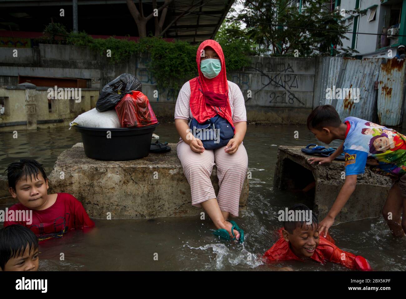 Jakarta, DKI Jakarta, Indonésie. 5 juin 2020. Une femme porte un masque facial assis sur un rocher en attendant d'être évacuée par l'équipe de secours. En raison du débordement de l'eau de mer qui s'instrite dans la zone côtière de Jakarta, certains résidents du nord de la région de Jakarta doivent évacuer le crédit : Muhammad Zaenuddin/ZUMA Wire/Alamy Live News Banque D'Images