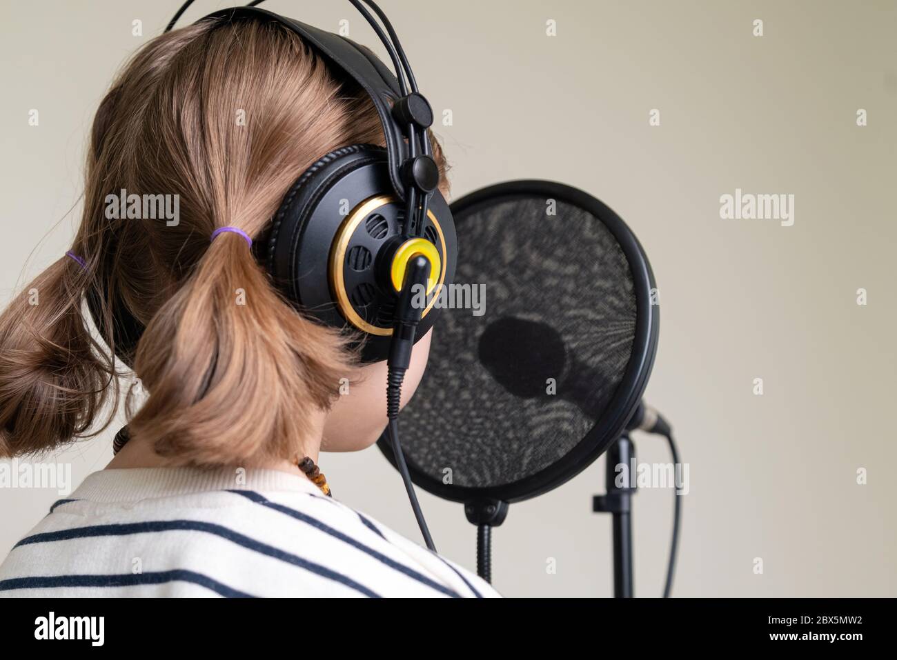 Gros plan sur l'enregistrement de musique d'adolescent dans un studio à domicile. Fille avec casque et enregistrement de chanson de microphone Banque D'Images