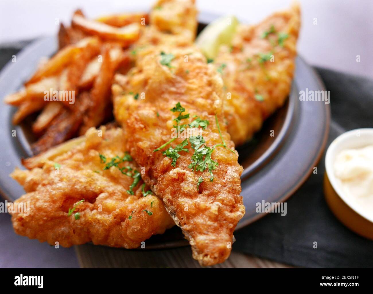 Poisson frit dans une pâte croustillante avec des frites coupées à la main Banque D'Images
