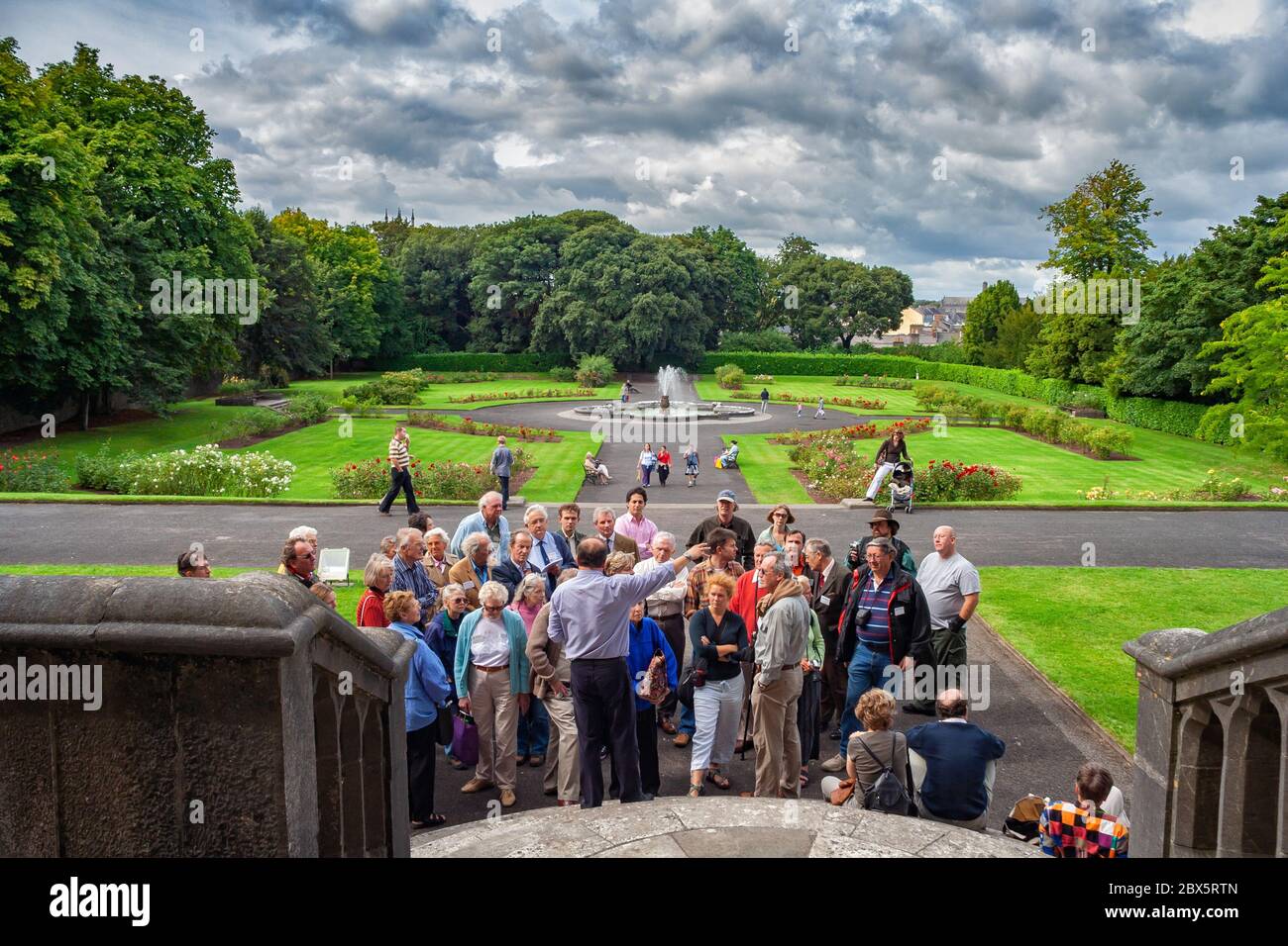 Groupe de touristes lors de la visite, les gens écoutent le guide de visite aux jardins du château de Kilkenny à Kilkenny, Irlande Banque D'Images