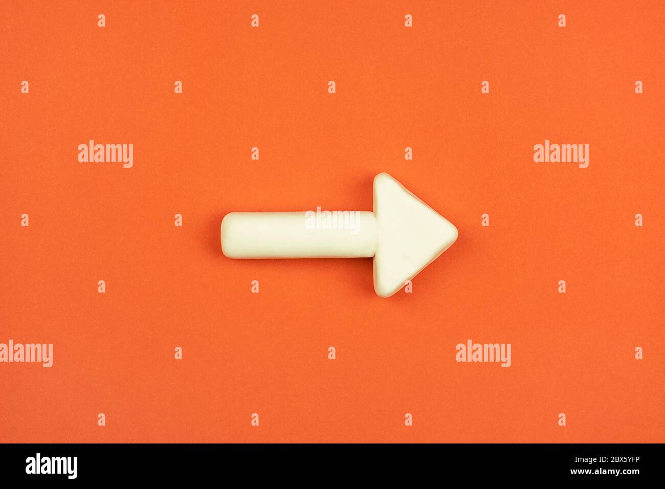 La flèche blanche sur l'arrière-plan rouge. Maquette 3D. Une indication de direction de pointage. Concept de bonne façon. Banque D'Images