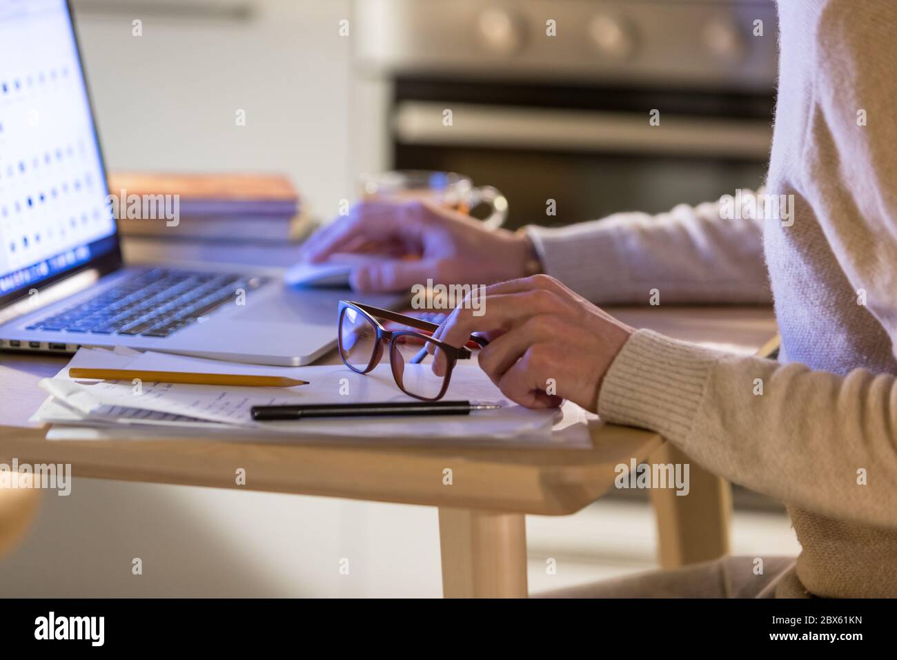 Homme indépendant travaillant au bureau à domicile sur ordinateur portable, se concentre sur les lunettes dans sa main. Travail à distance, travail en ligne à distance Banque D'Images