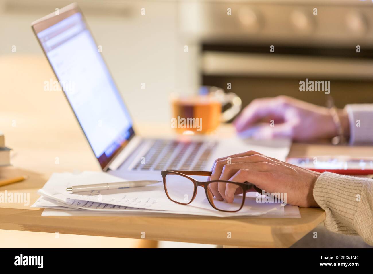 Image rognée d'un homme assis et travaillant au bureau à domicile via un ordinateur portable, et en cliquant sur la souris numérique sans fil, se concentrer sur les lunettes à portée de main. Coupe de t. Floue Banque D'Images