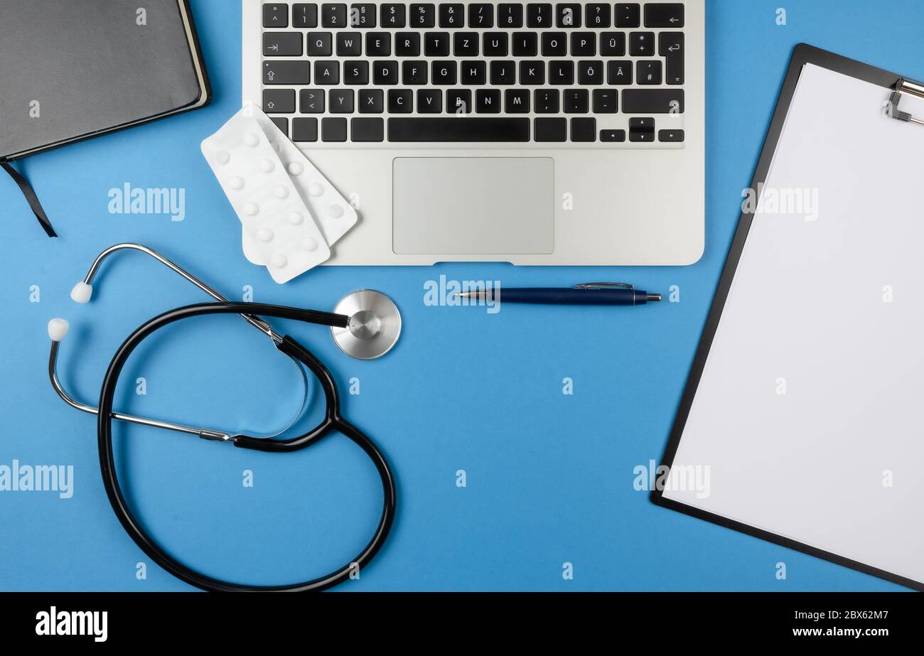 vue de dessus du bureau du médecin ou du médecin avec stéthoscope, ordinateur portable, livre et presse-papiers avec feuilles de papier Banque D'Images