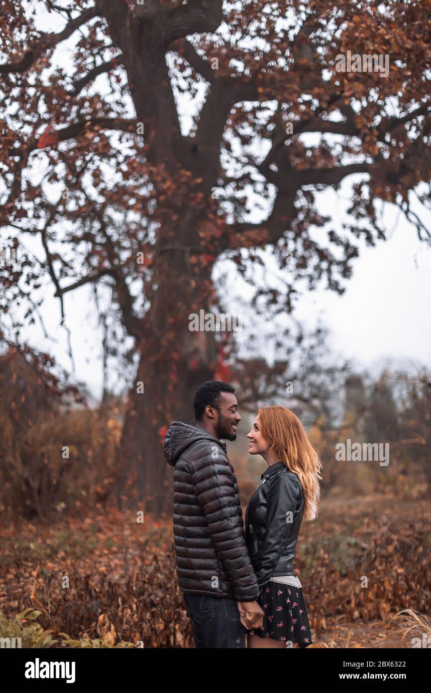 Couple interracial posant en automne feuilles fond, homme noir et femme blanc à tête rouge Banque D'Images