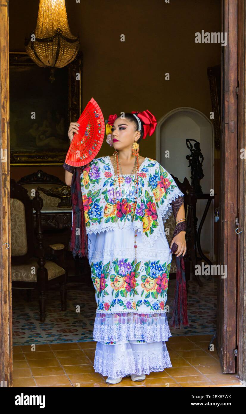 Merida,Yucatan/Mexico-février 29,2020: Femme en tunique huipil brodée traditionnelle et supports habit avec son ventilateur rouge dans la porte de l'Hacienda Banque D'Images