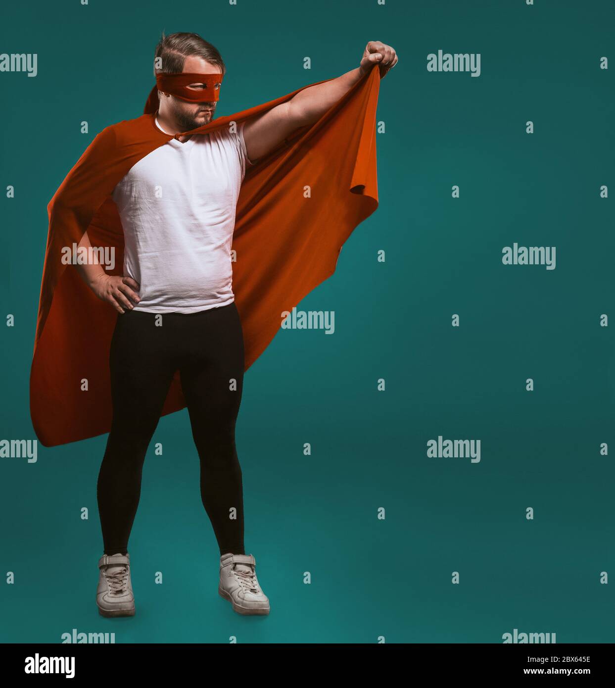 Super héros sauveur homme prêt à voler. Le brave homme légendaire en masque rouge tient son manteau prêt à sauver le monde du crime. Isolé sur vert de gascogne Banque D'Images