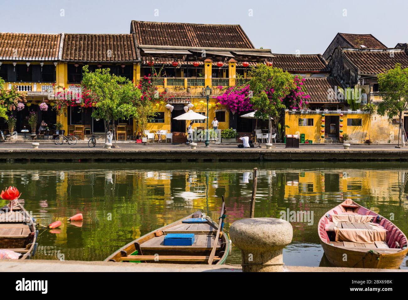 Scène de la vieille ville historique de Hoi an le long de la rivière avec des bateaux, lanternes, fleurs et les bâtiments jaune or Hoi an avec des toits de tuiles Banque D'Images