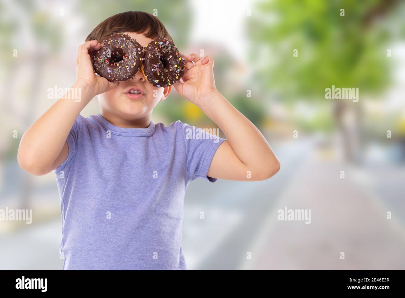 Petit garçon enfant avec beignes beignes ayant plaisir bonheur heureux ville malsain manger à l'extérieur Banque D'Images