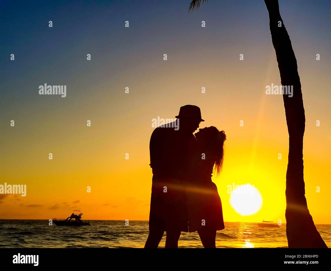 Silhouette de couple sur la plage au coucher du soleil avec bateau en arrière-plan. Plage de Grand Bahia principe à Punta Cana, République Dominicaine. Banque D'Images