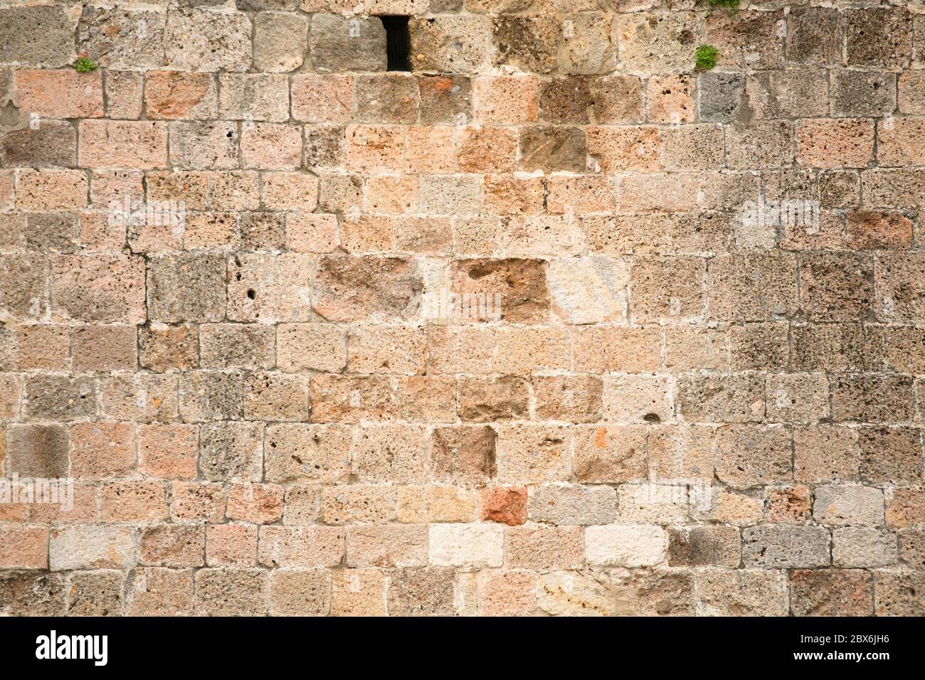 Texture de mur calcaire. Mur d'un vieux bâtiment avec une petite fenêtre et un peu trop cultivé avec de l'herbe. Arrière-plan abstrait Banque D'Images