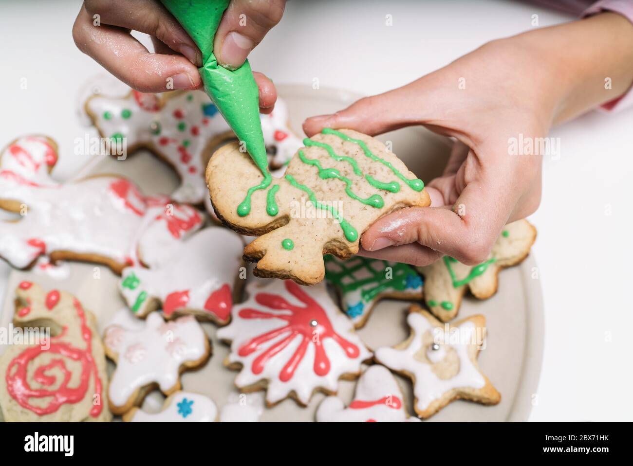 Les mains de petite fille faisant des biscuits de Noël traditionnels. L'enfant décorera les biscuits de Noël faits maison sur une table blanche Banque D'Images