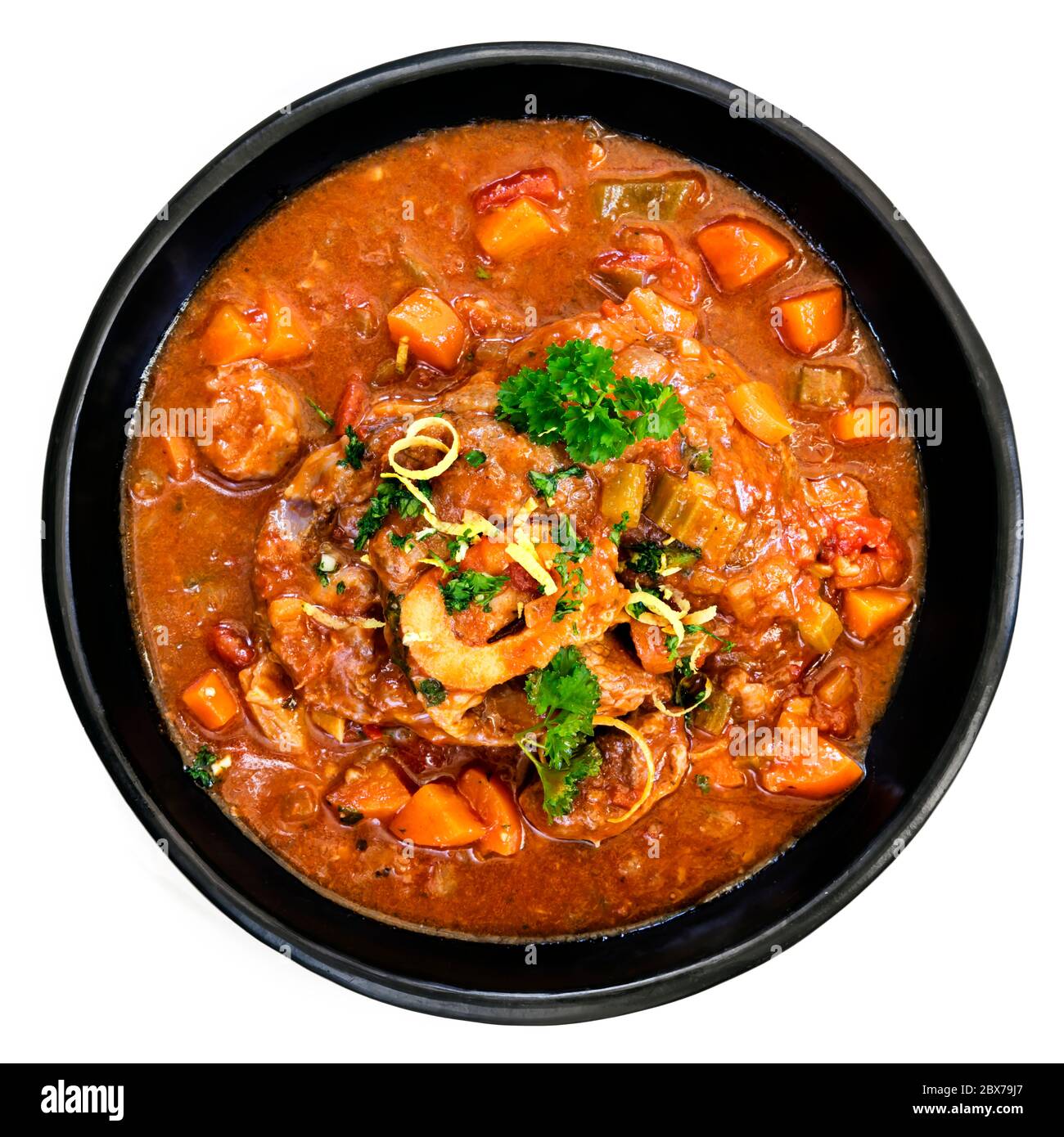 Osso buco jarret de veau cocotte dans un plat noir rustique. Vue de dessus, isolée sur blanc. Banque D'Images