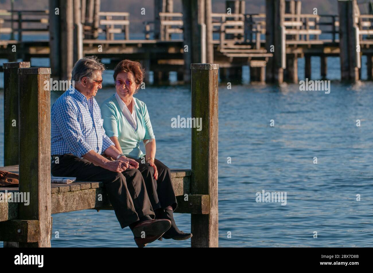 Un couple de personnes âgées heureux assis au bord de l'eau Banque D'Images