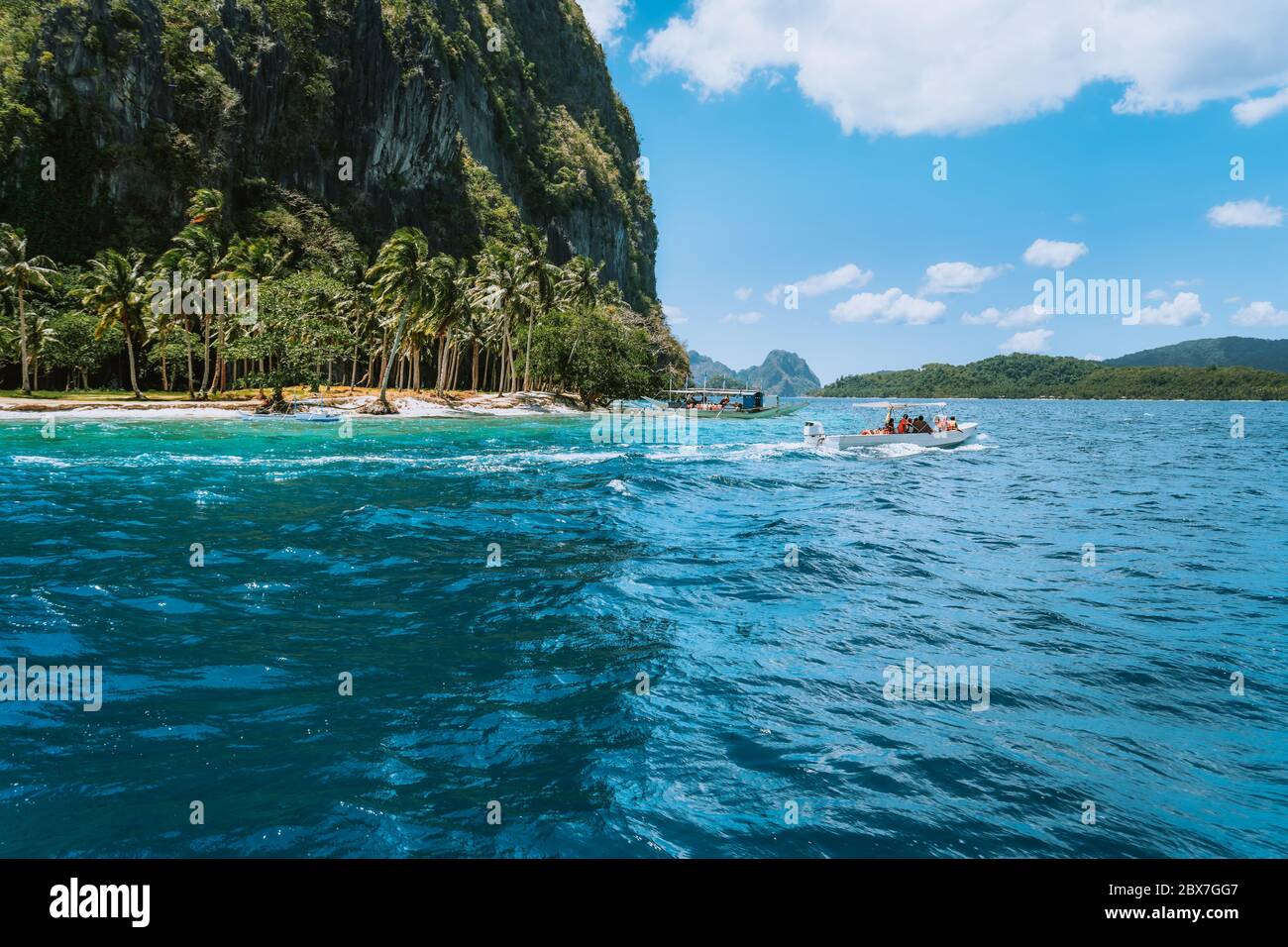 Bateau avec des touristes sur la plage de l'ipil de l'île exotique sur le tour de saut, archipel de Bahuit, El Nido, Palawan, Philippines Banque D'Images