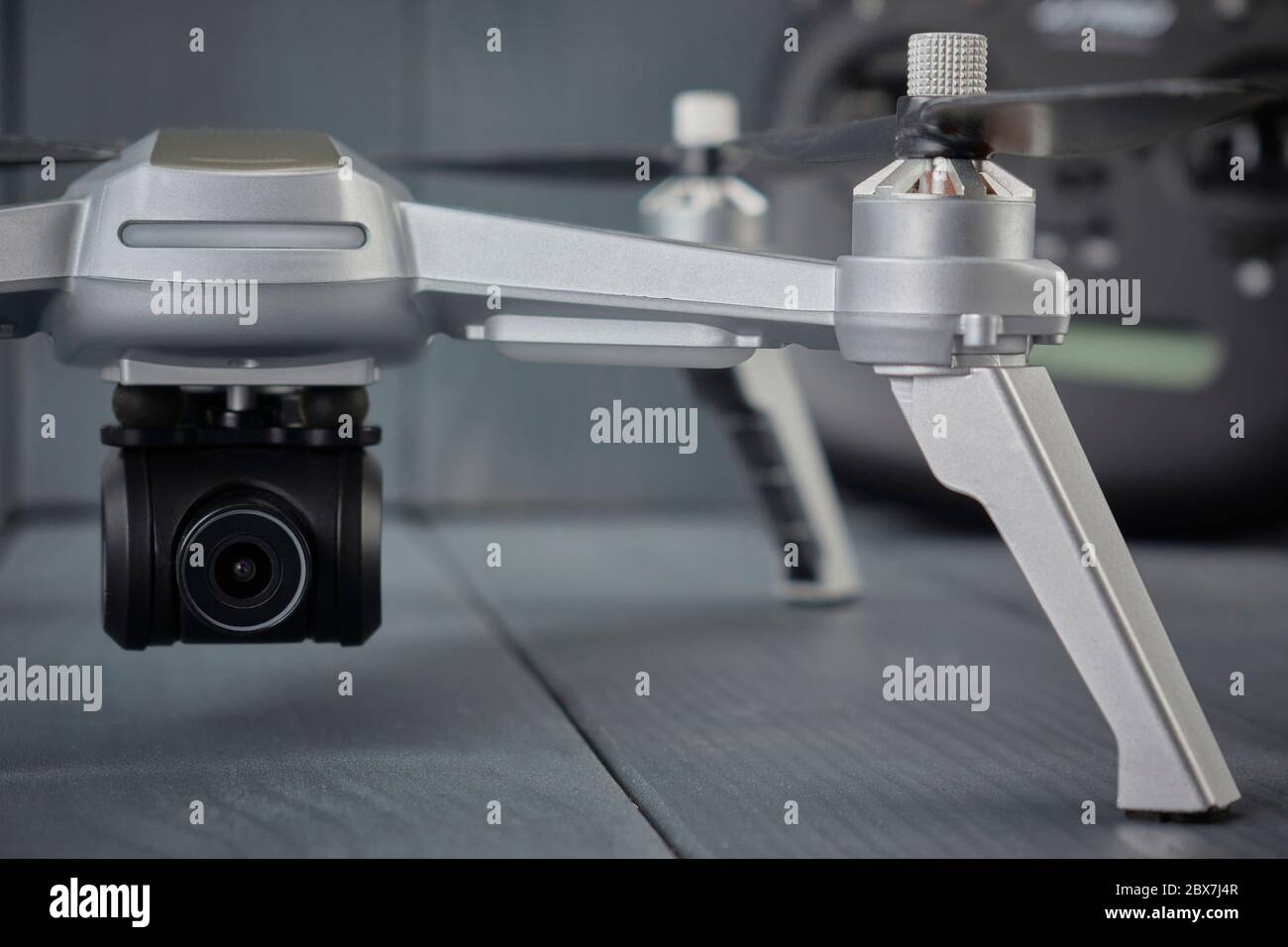 Gros plan de la caméra à quatre moteurs montée sur drone et de la télécommande à double fréquence à l'arrière-plan sur fond gris en bois Banque D'Images