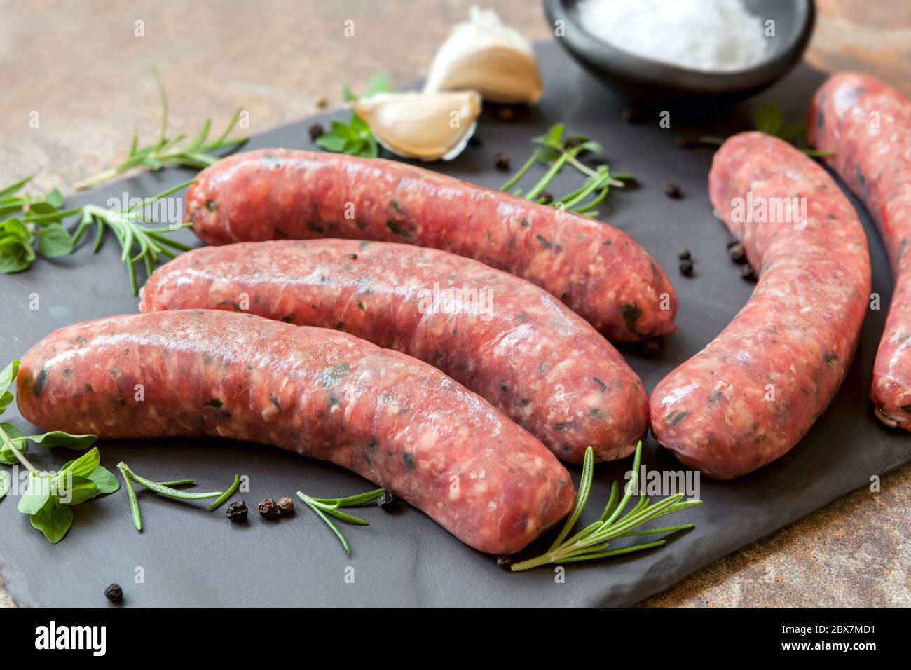 Saucisses crues sur ardoise, avec herbes et épices. Vue latérale. Banque D'Images
