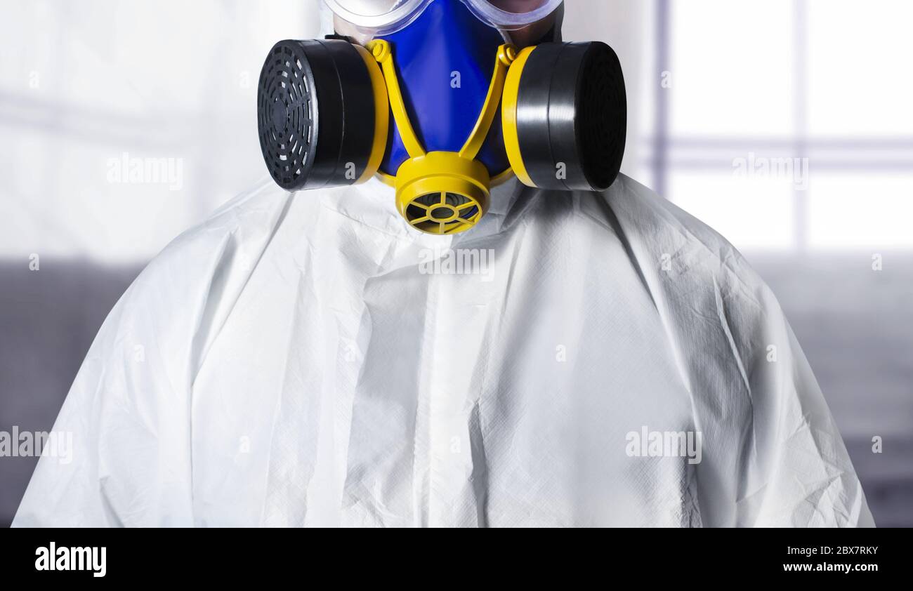 Travailleur en costume de protection et respirateur debout, vue rapprochée sur le fond de la zone de peinture. Banque D'Images