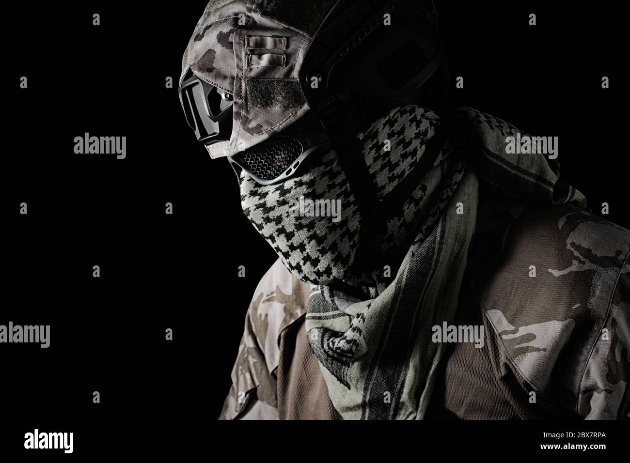 Tête de soldat militaire avec casque de camouflage, lunettes de protection et vue du profil du foulard militaire sur fond noir. Banque D'Images