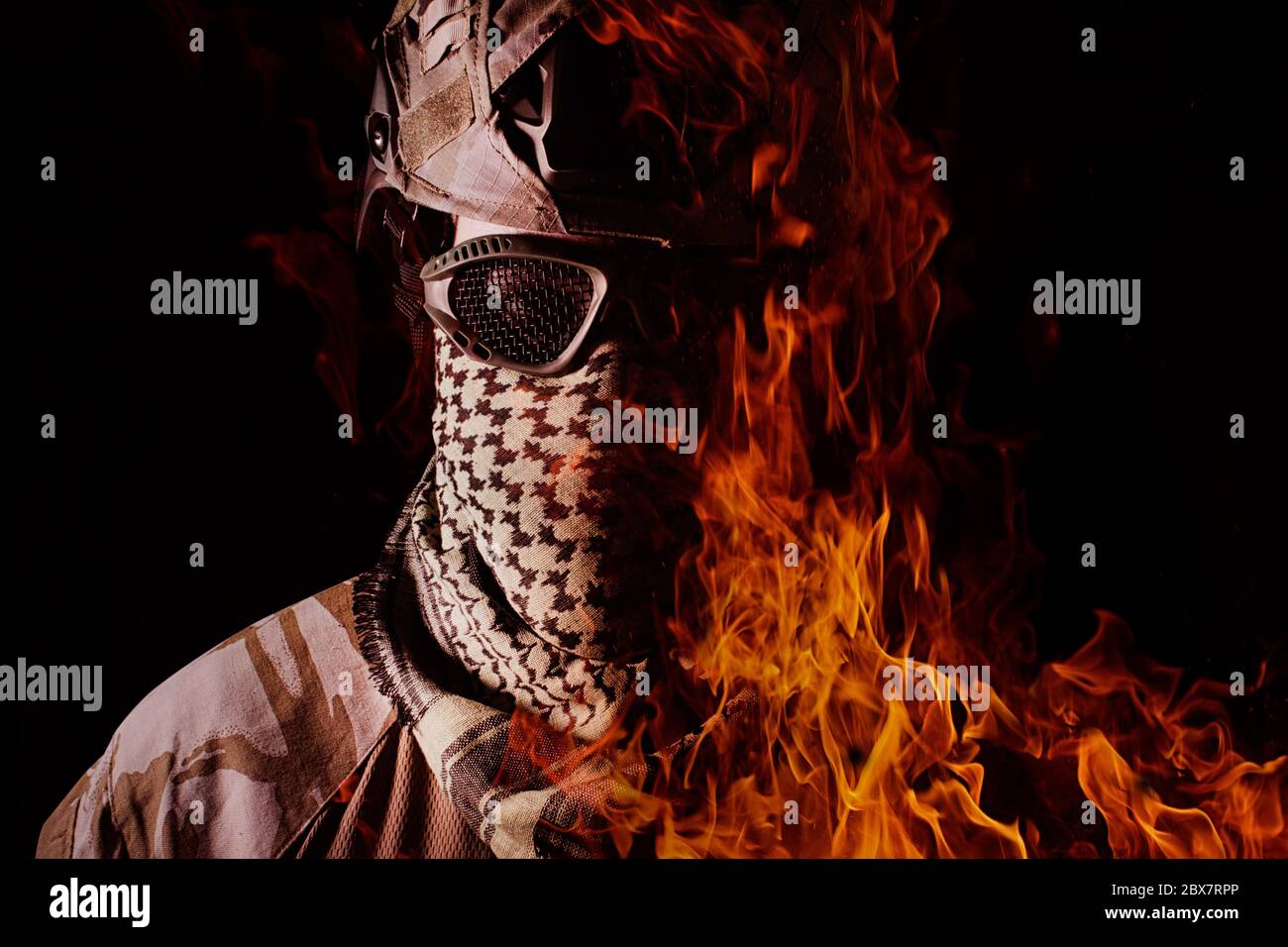 Portrait de soldat militaire avec visage en feu, casque de camouflage, lunettes de protection et foulard militaire vue rapprochée sur fond noir. Banque D'Images