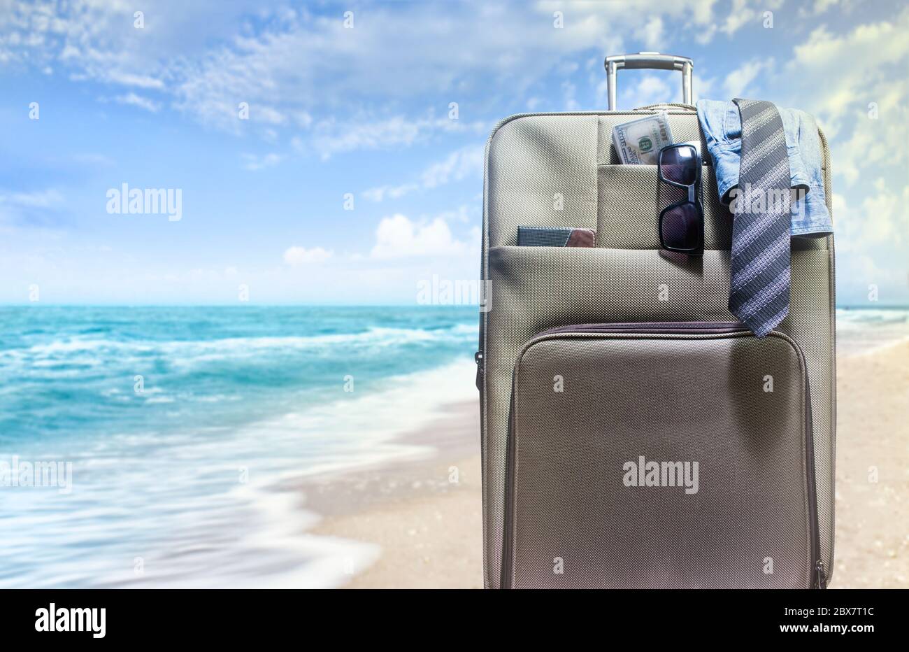 Photo d'une valise de voyage emballée avec une chemise, une cravate, de  l'argent et des lunettes de soleil sur un fond ensoleillé de plage Photo  Stock - Alamy
