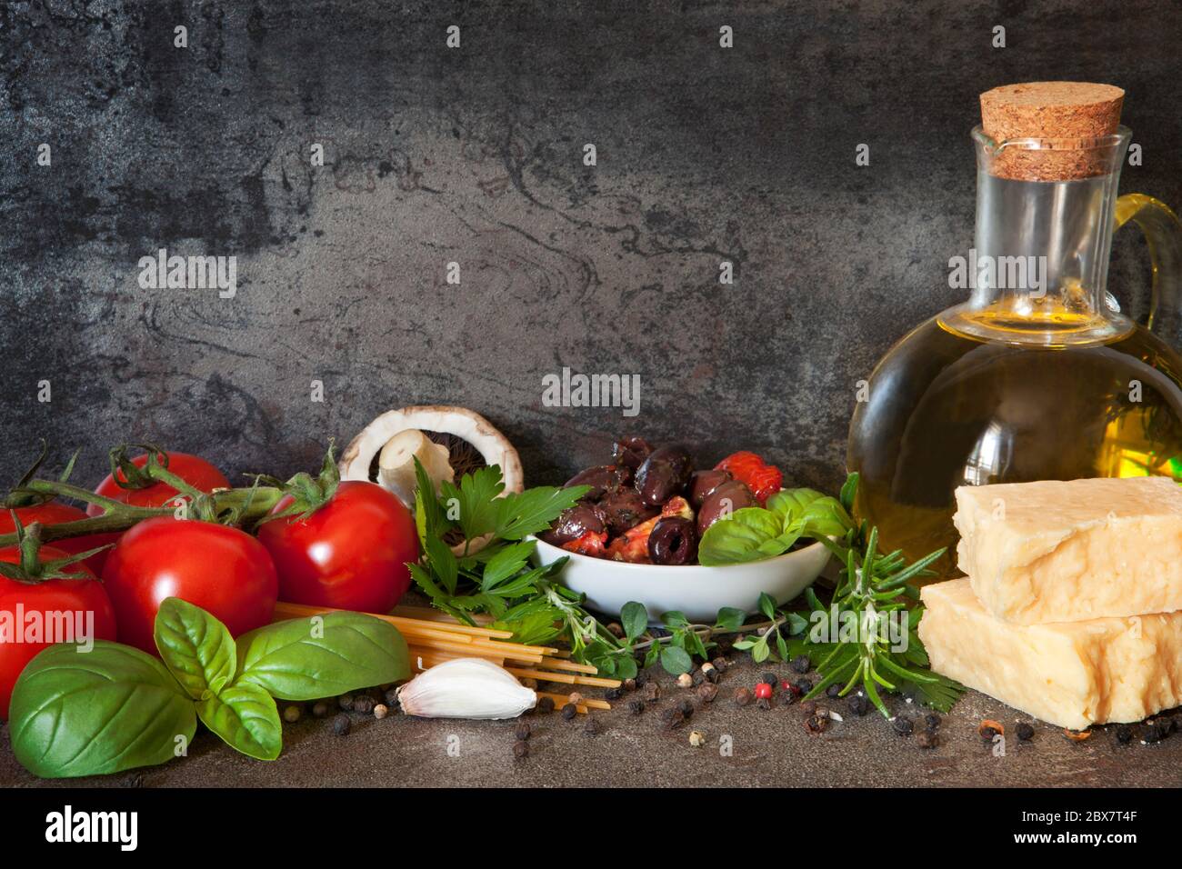 Cuisine italienne, avec tomates de vigne, basilic, spaghetti, champignons, olives, parmesan, huile d'olive, ail, grains de poivre, romarin, persil et thym Banque D'Images