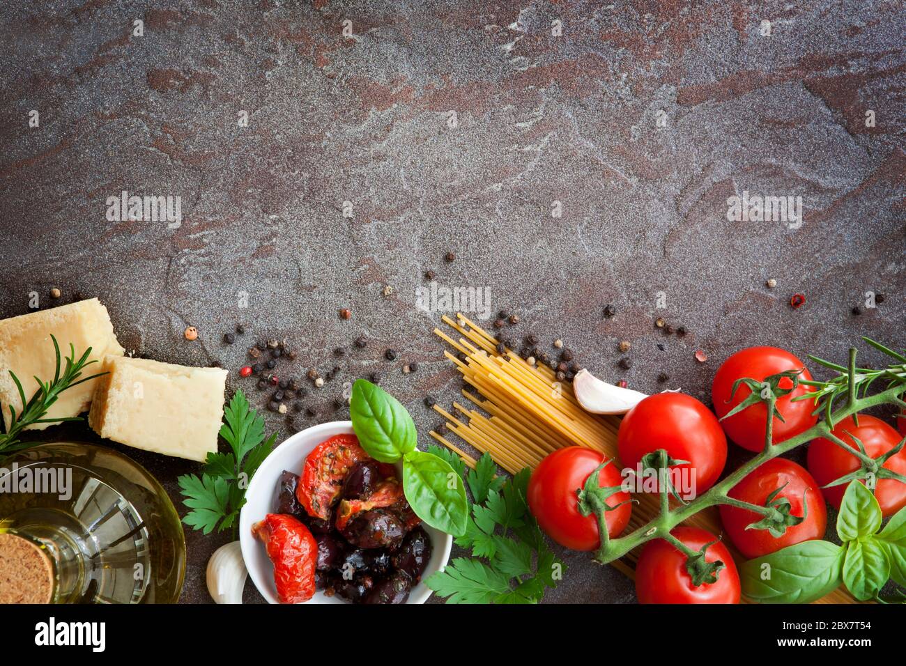 Cuisine italienne, avec tomates de vigne, basilic, spaghetti, champignons, olives, parmesan, huile d'olive, ail, grains de poivre, romarin, persil et thym Banque D'Images
