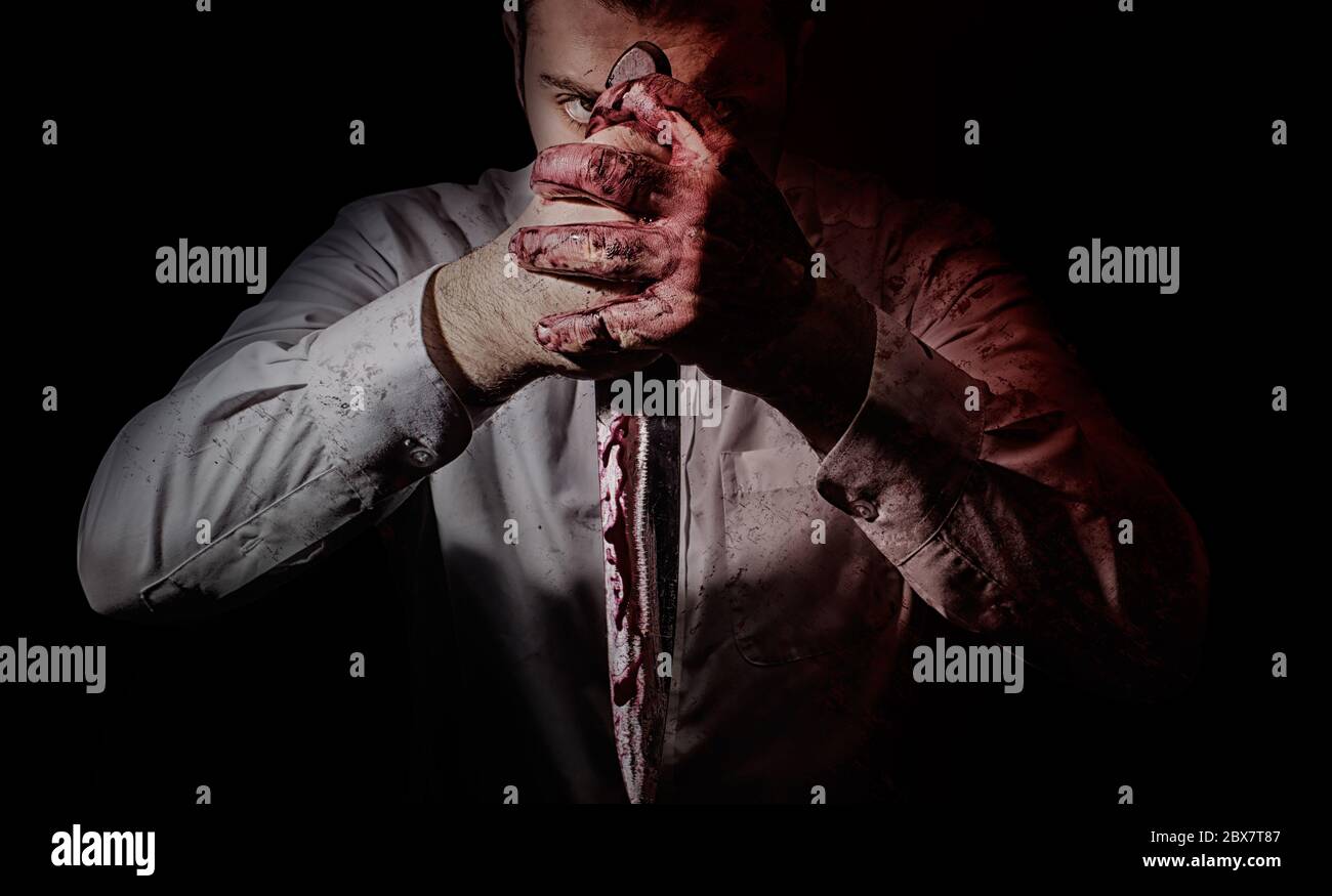 Photo d'horreur d'un meurtrier assoiffé de sang posant avec un gros couteau de cuisine sanglant tenant dans les deux mains. Banque D'Images