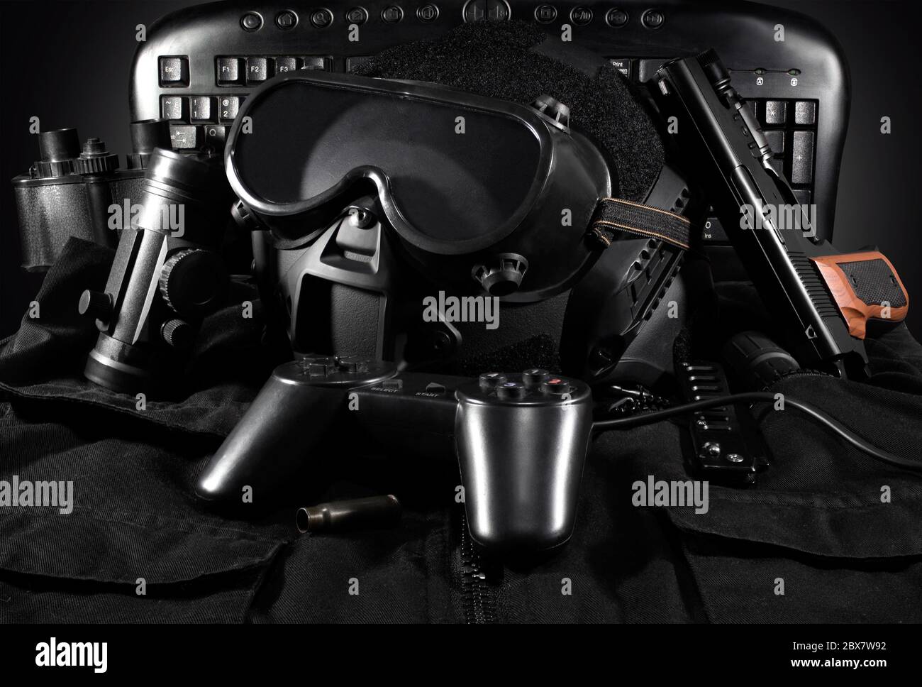 Casque tactique, gants, pistolet, jumelles, posé sur une veste avec manette de jeu et clavier sur fond. Banque D'Images