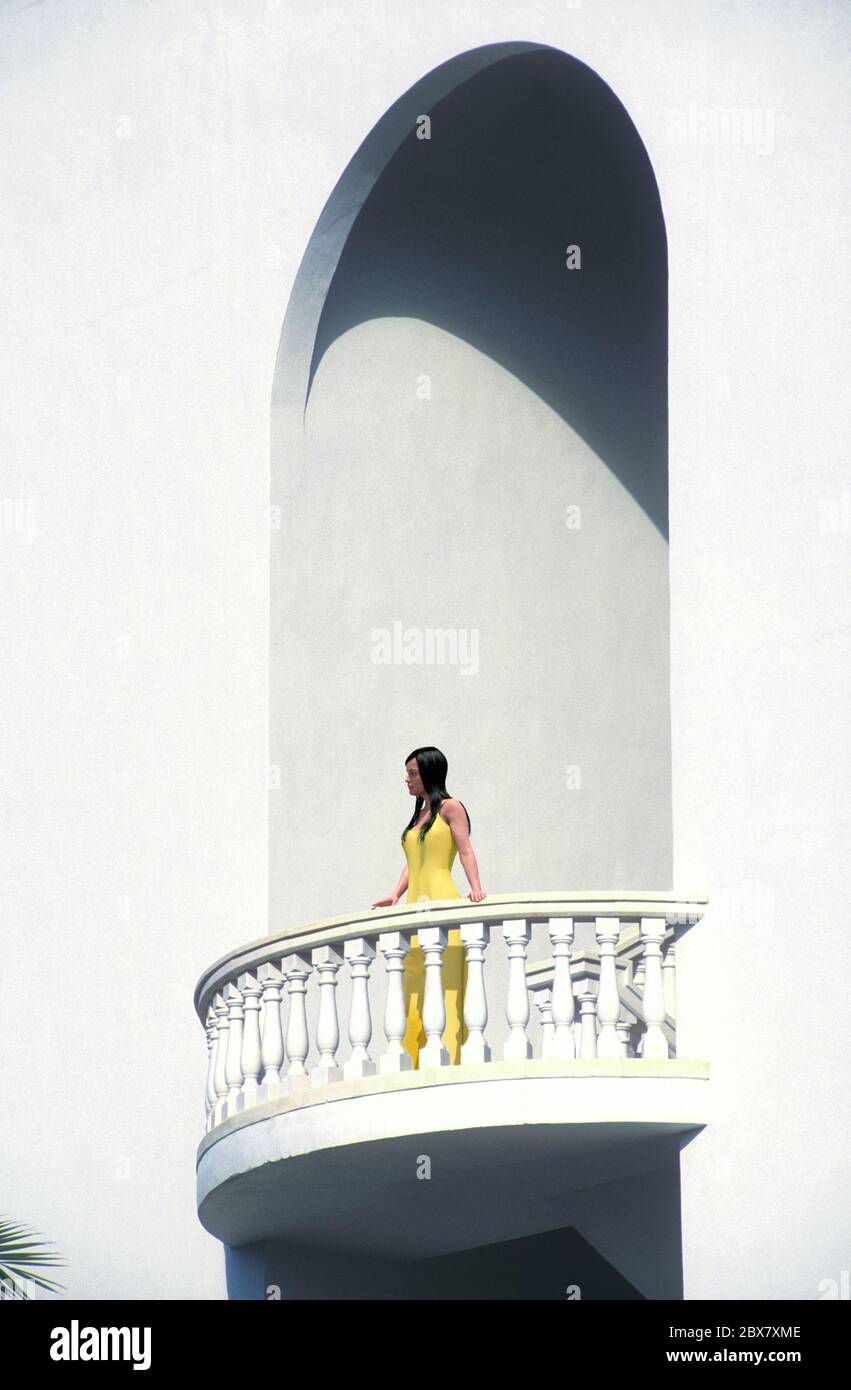 Femme dans une robe jaune debout sur un balcon avec arche, Resort Hotel, Mallorca, Espagne. Banque D'Images